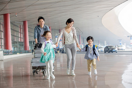 提着行李男孩欢乐家庭在机场推着行李背景