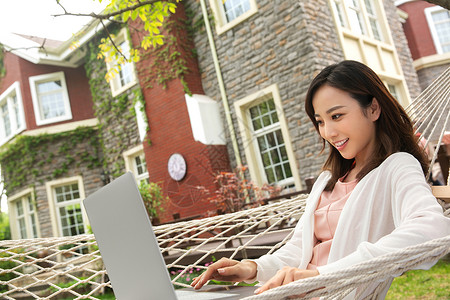 青年女人在院子里用笔记本电脑高清图片