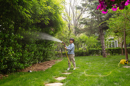 绿化家园快乐的小男孩在院子里浇水背景