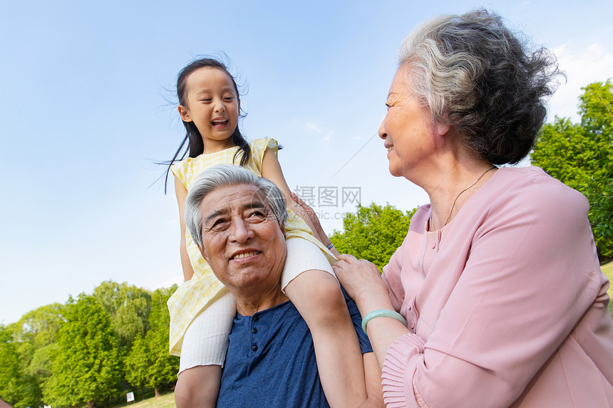 老年夫妇带着孙女在公园里郊游图片