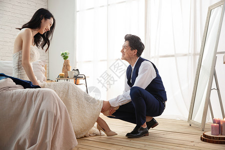 年轻的丈夫蹲下给妻子穿鞋高清图片