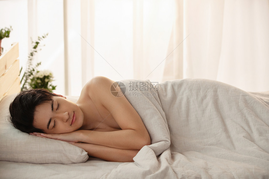 躺在床上睡觉的年轻男人图片