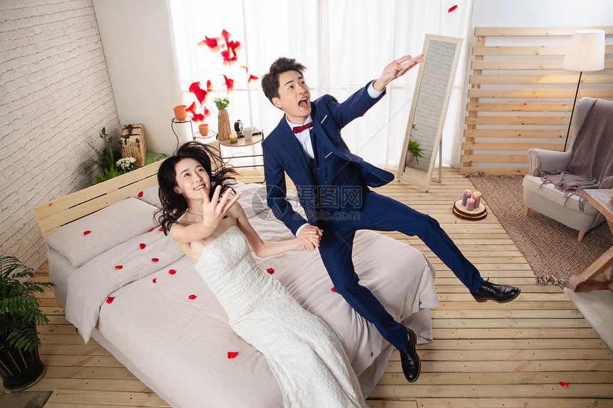 兴奋的新婚夫妇倒在床上图片