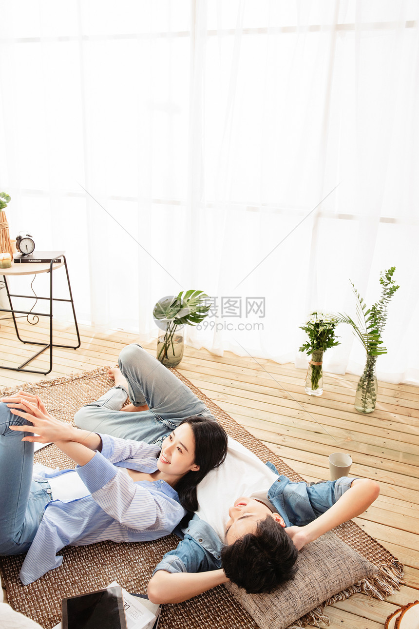 快乐情侣躺在地毯上享受午后时光图片