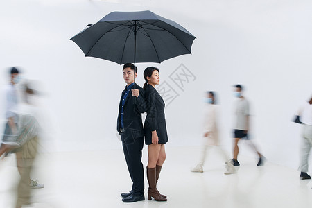 拿着雨伞的商务男女站在人群中图片素材