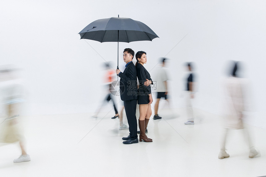 拿着雨伞的商务男女站在人群中图片