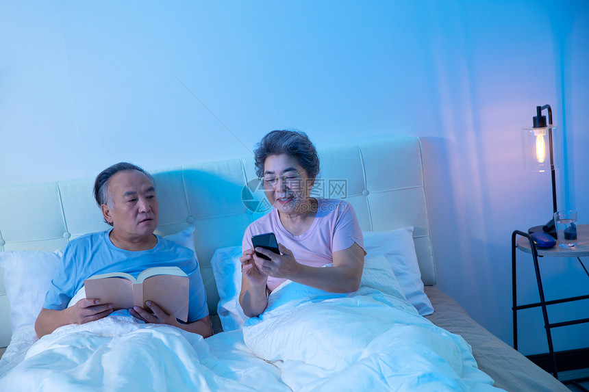 老年夫妇坐在床上看手机图片
