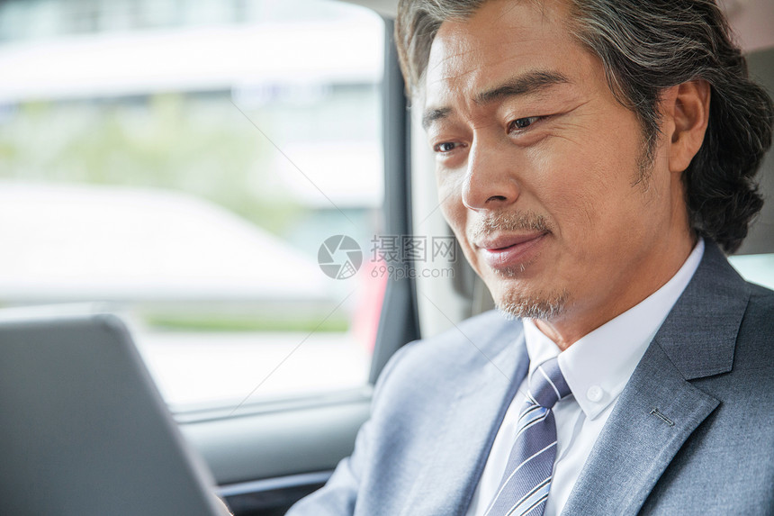 商务男士坐在汽车里看平板电脑图片