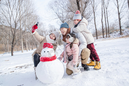 欢乐家庭在雪地里堆雪人高清图片