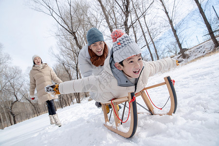 玩雪儿童在雪地上玩雪橇的一家人背景