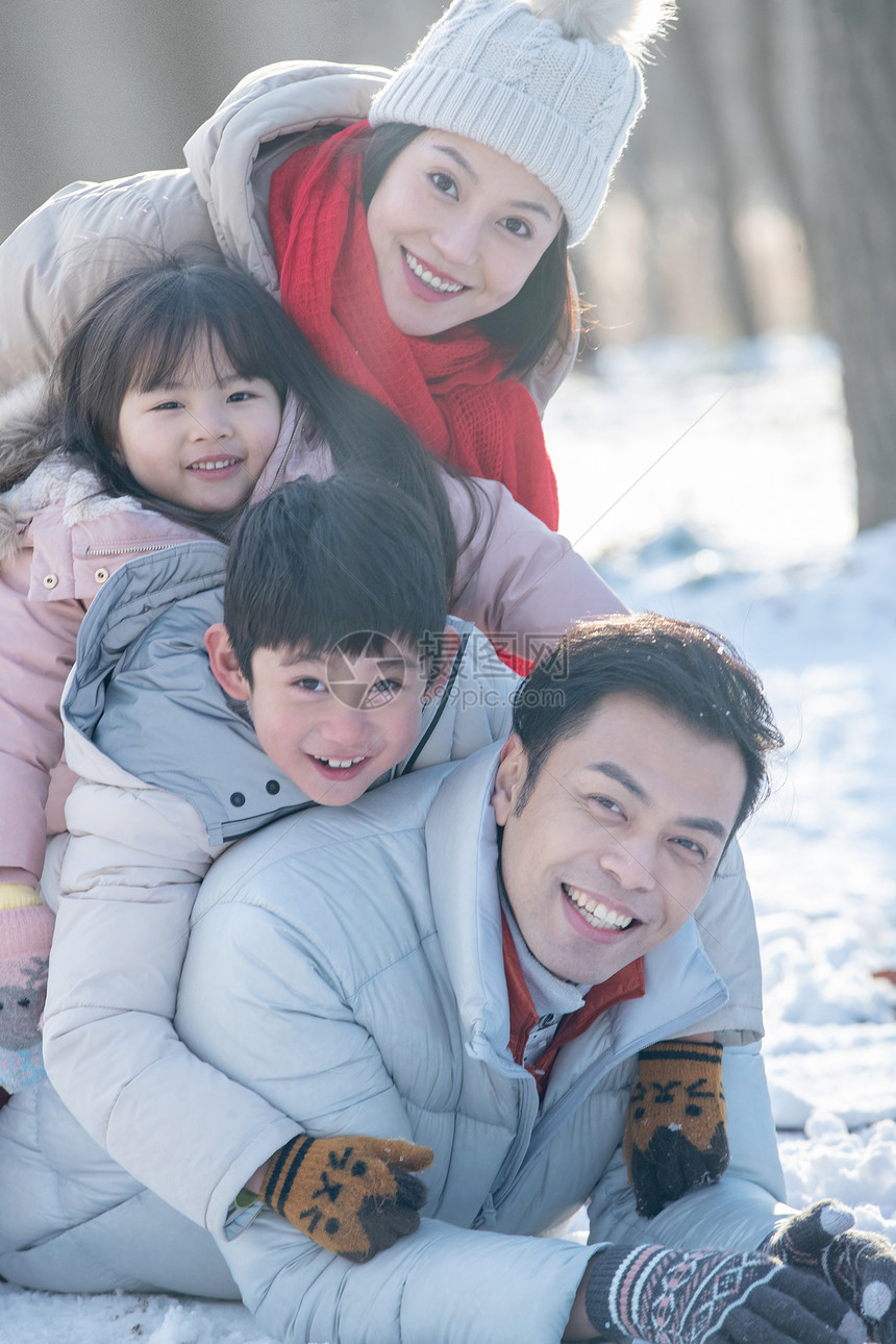趴在雪地里玩耍的快乐家庭图片