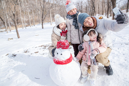 欢乐家庭在雪地里堆雪人高清图片