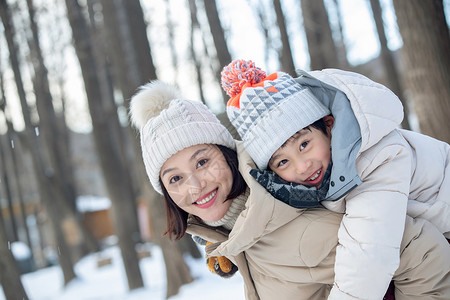 年轻妈妈带着孩子在雪地玩耍图片