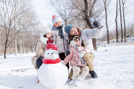 欢乐家庭在雪地里堆雪人高清图片