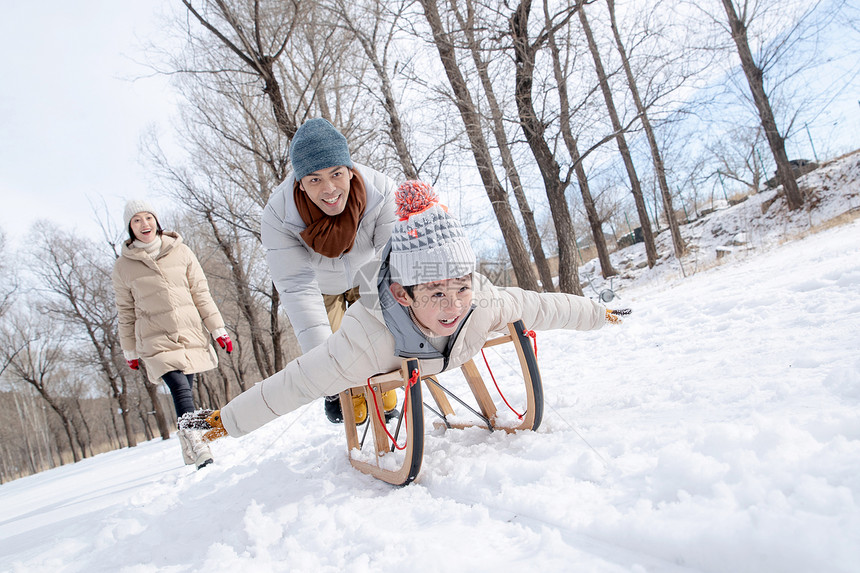 推雪橇玩耍的一家人图片