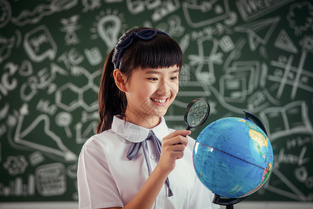 小学女生拿着放大镜看地球仪校服高清图片素材