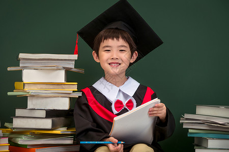 教科书文凭穿着学士服的小学男生背景