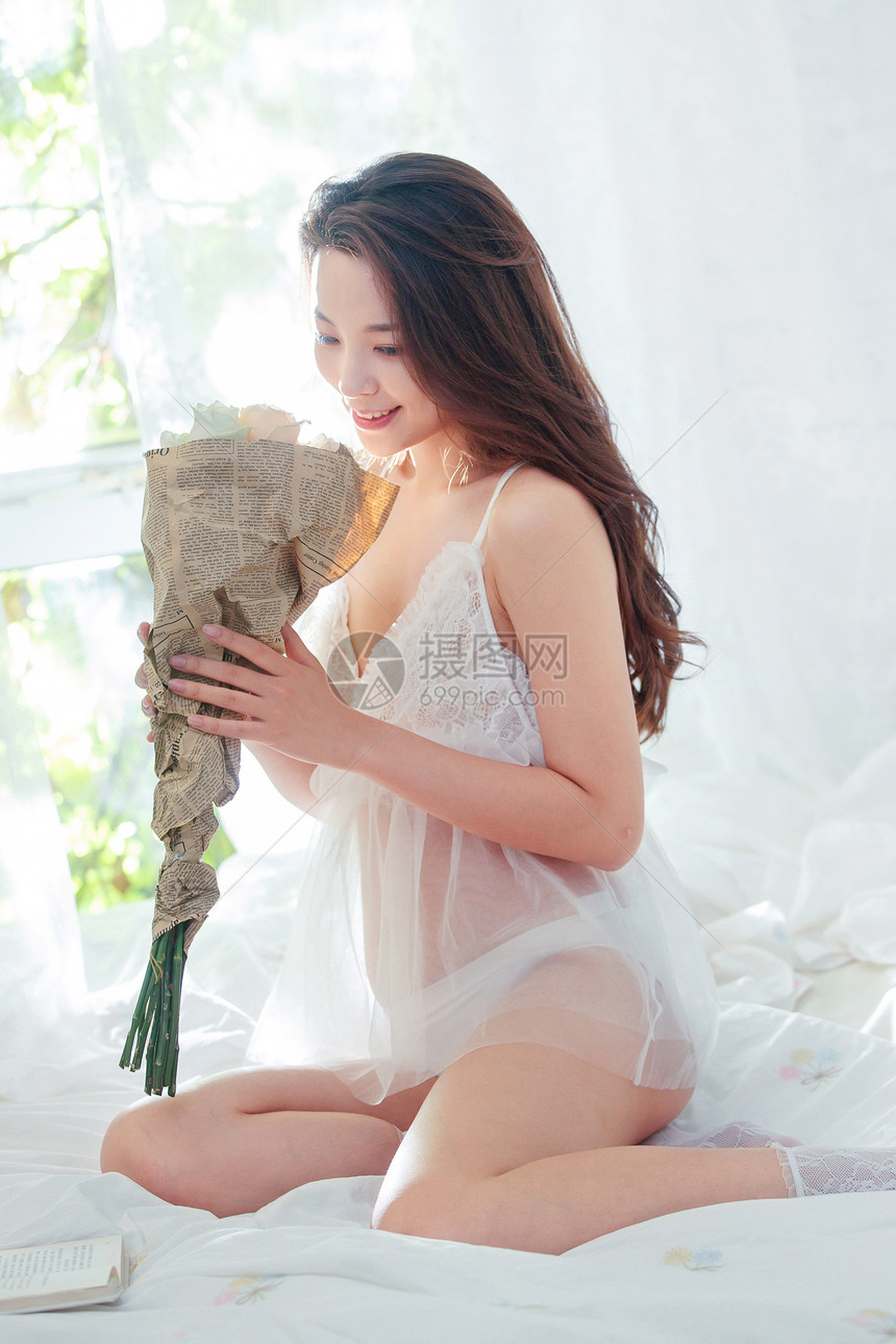 坐在床上的漂亮青年女人捧着花图片