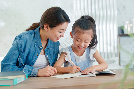 作业指导书辅导女儿做作业的青年女人背景