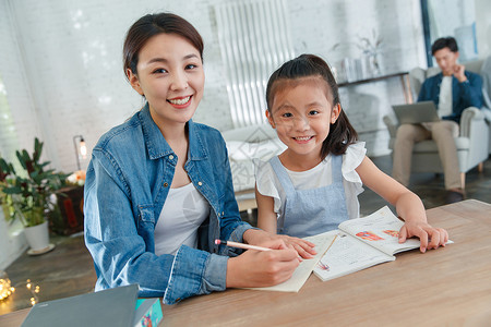 漂亮的青年女人辅导女儿写作业写字高清图片素材