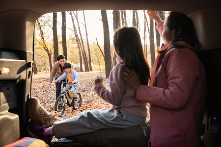 先学车后幸福母女在车中向学自行车的父子打招呼背景