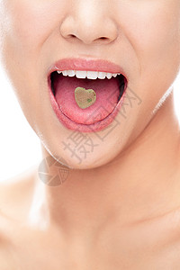 舌头口腔舌头上有颗心形糖的青年女人嘴部特写背景