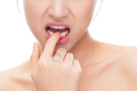 用手指触碰牙齿的青年女人图片