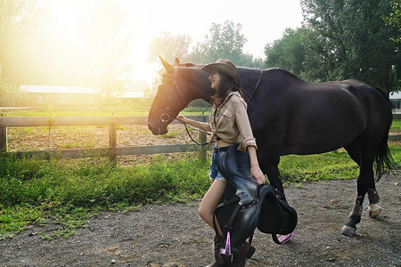 马场内时尚活力的青年女人牵着马图片