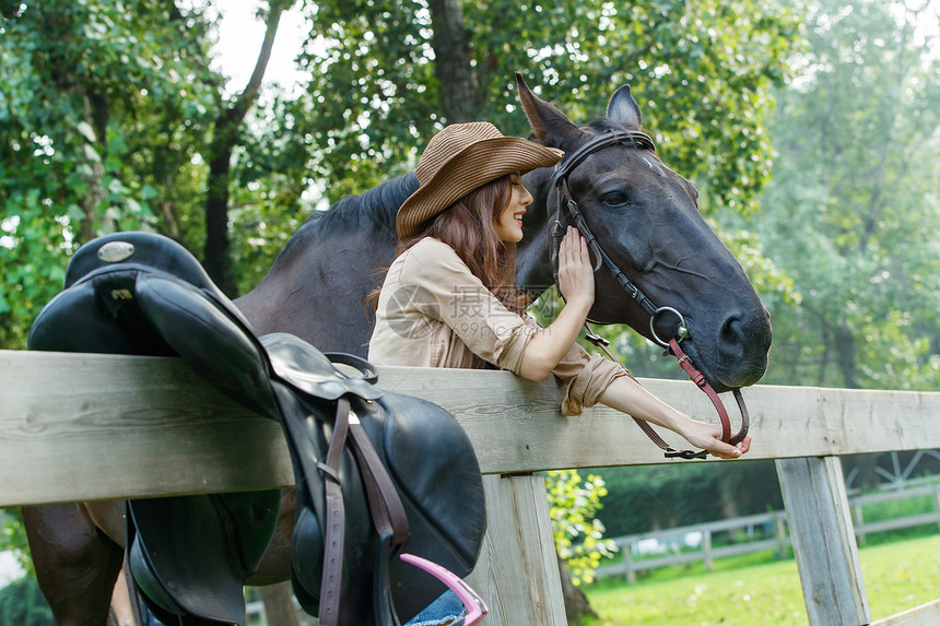 围栏旁抚摸马的个女孩图片