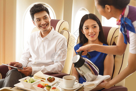 年轻夫妇在飞机上用餐高清图片