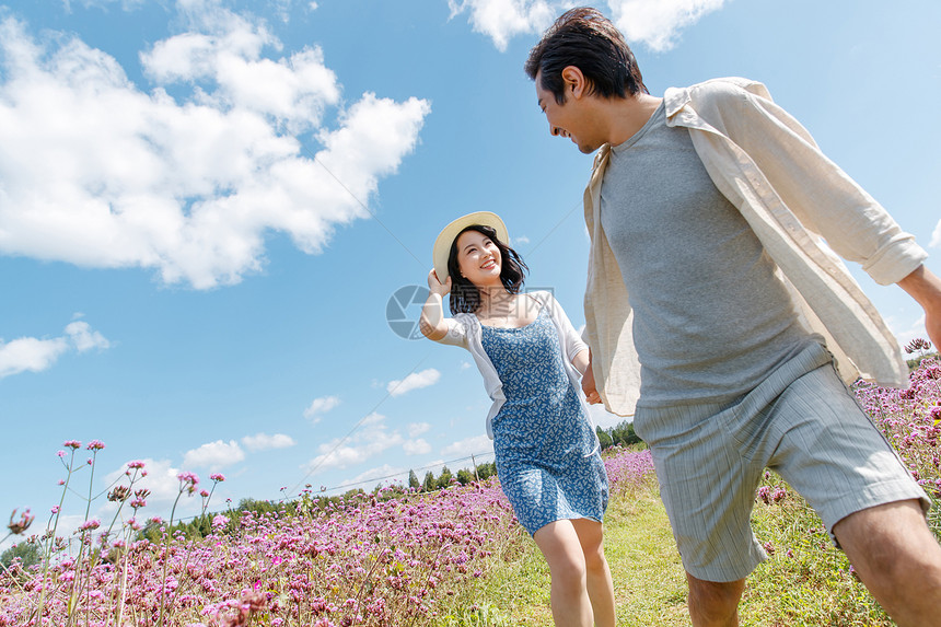 青年夫妇手牵手在花海里奔跑图片