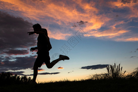 夕阳下跳跃的人夕阳下跳跃的青年男人背景