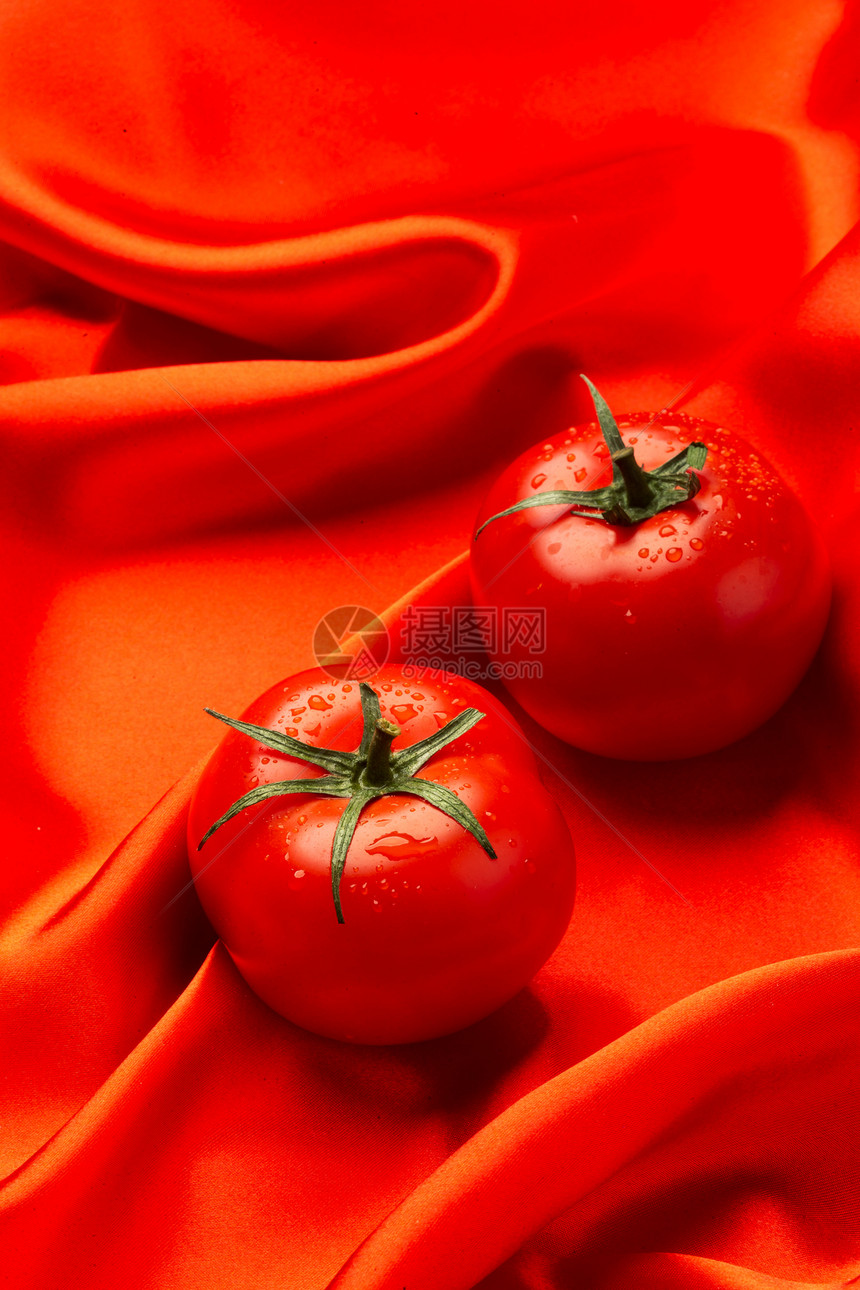 红色丝绸上摆放西红柿图片