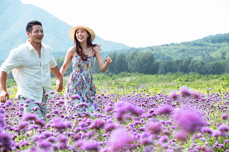 青年夫妇手牵手走在花海里高清图片