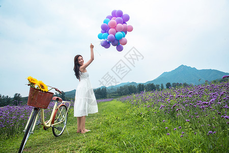 自行车鲜花气球青年女人站在花海里背景