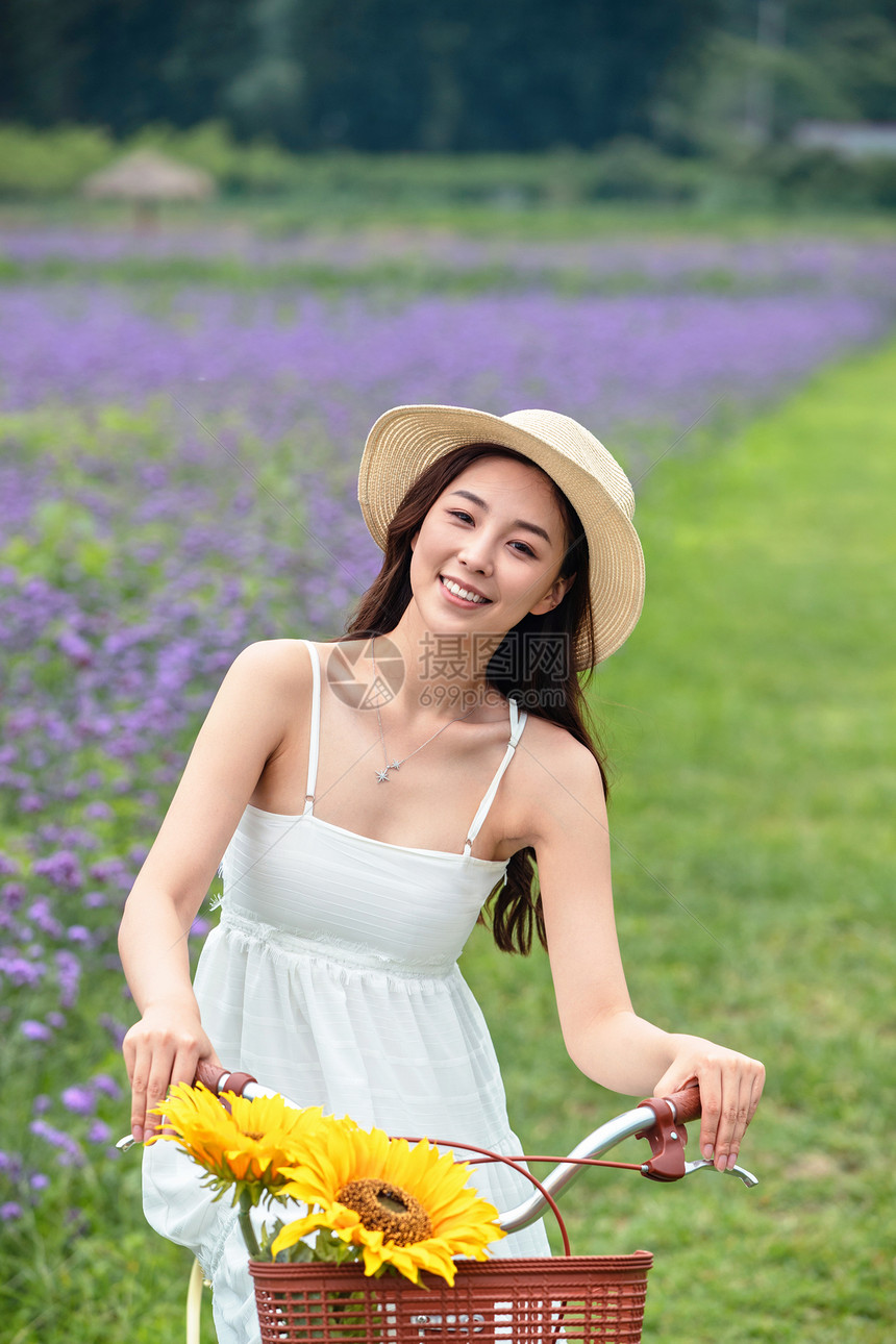 青年女人在花海里骑自行车图片