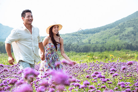 青年夫妇手牵手走在花海里高清图片