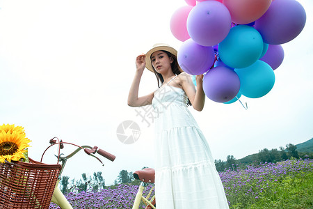 自行车鲜花气球青年女人在花海里拿着气球背景