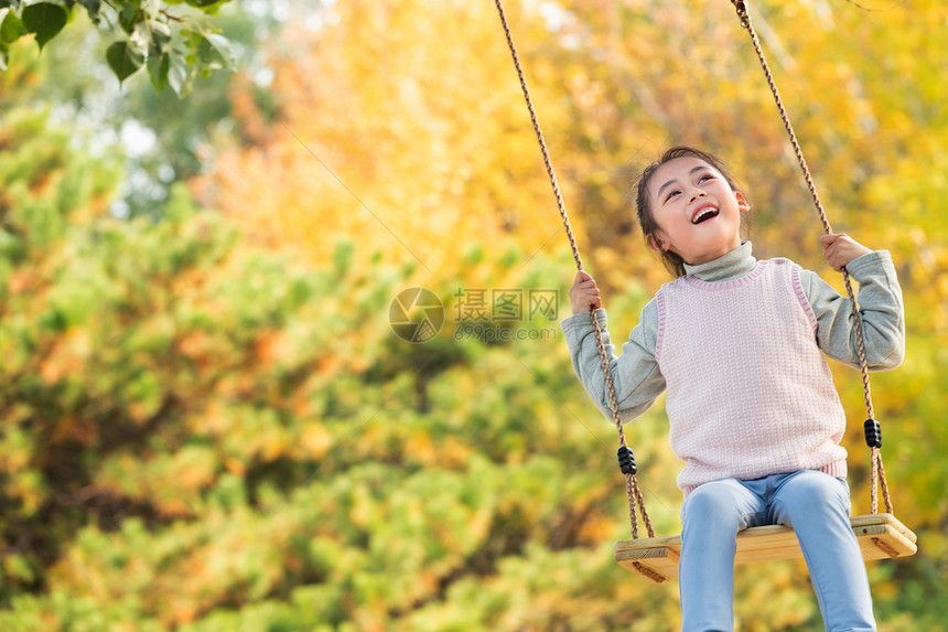 快乐的小女孩在公园里荡秋千图片