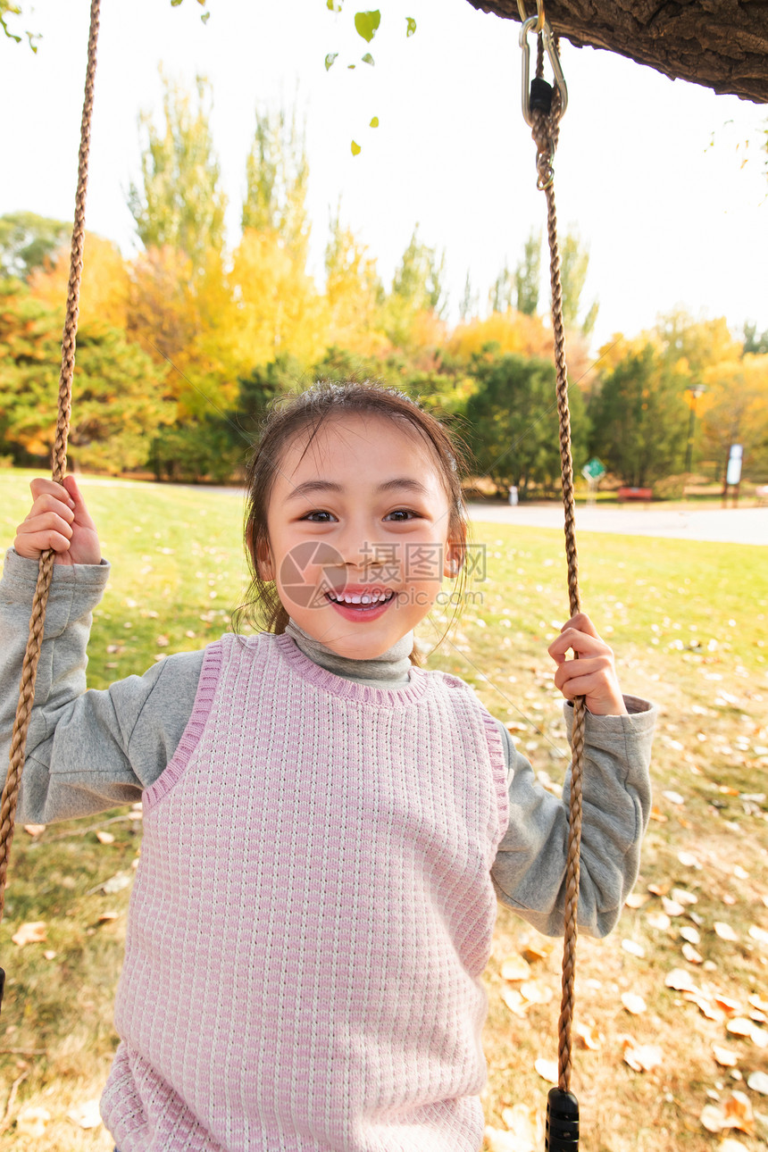 快乐的小女孩在公园里荡秋千图片