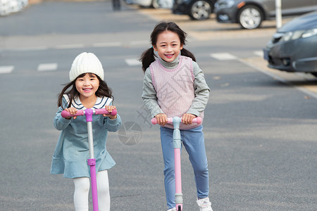 女孩在玩滑板车快乐的小女孩在户外玩滑板车背景