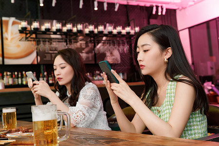 在酒吧里玩手机的青年女人俱乐部高清图片素材