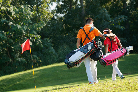 青年男休闲学习球场上教练和学生背着高尔夫球包步行的背影背景