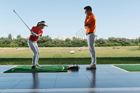 练习场上教练指导女童打高尔夫高清图片