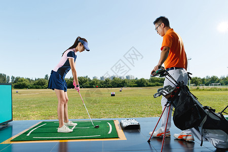 男人女人打球练习场上教练指导青年女人打高尔夫背景