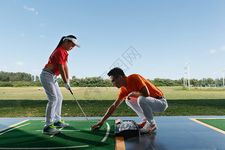 户外教学练习场上教练指导女童打高尔夫背景