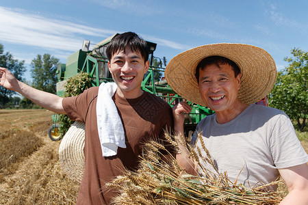 抱着麦穗农民农田里实现机械化收割的农民背景