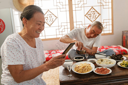 老年夫妇在家里吃饭看手机高清图片