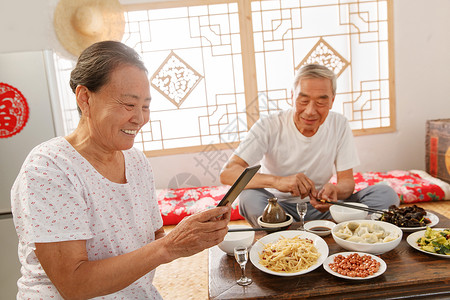 老年夫妇在家里吃饭看手机图片素材