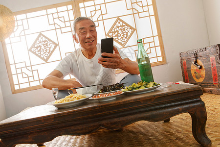 老年人坐在家里吃饭看手机图片素材